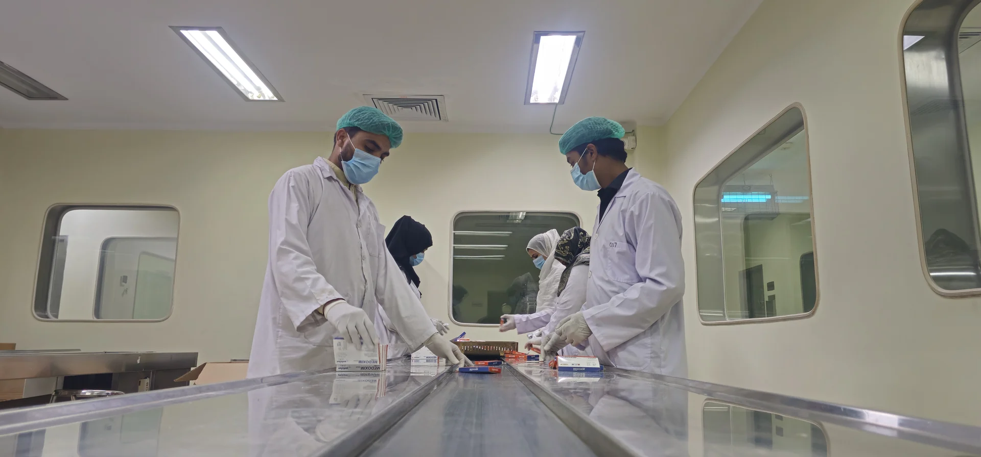 HiMedic personnel in protective gowns handling pharmaceutical packaging